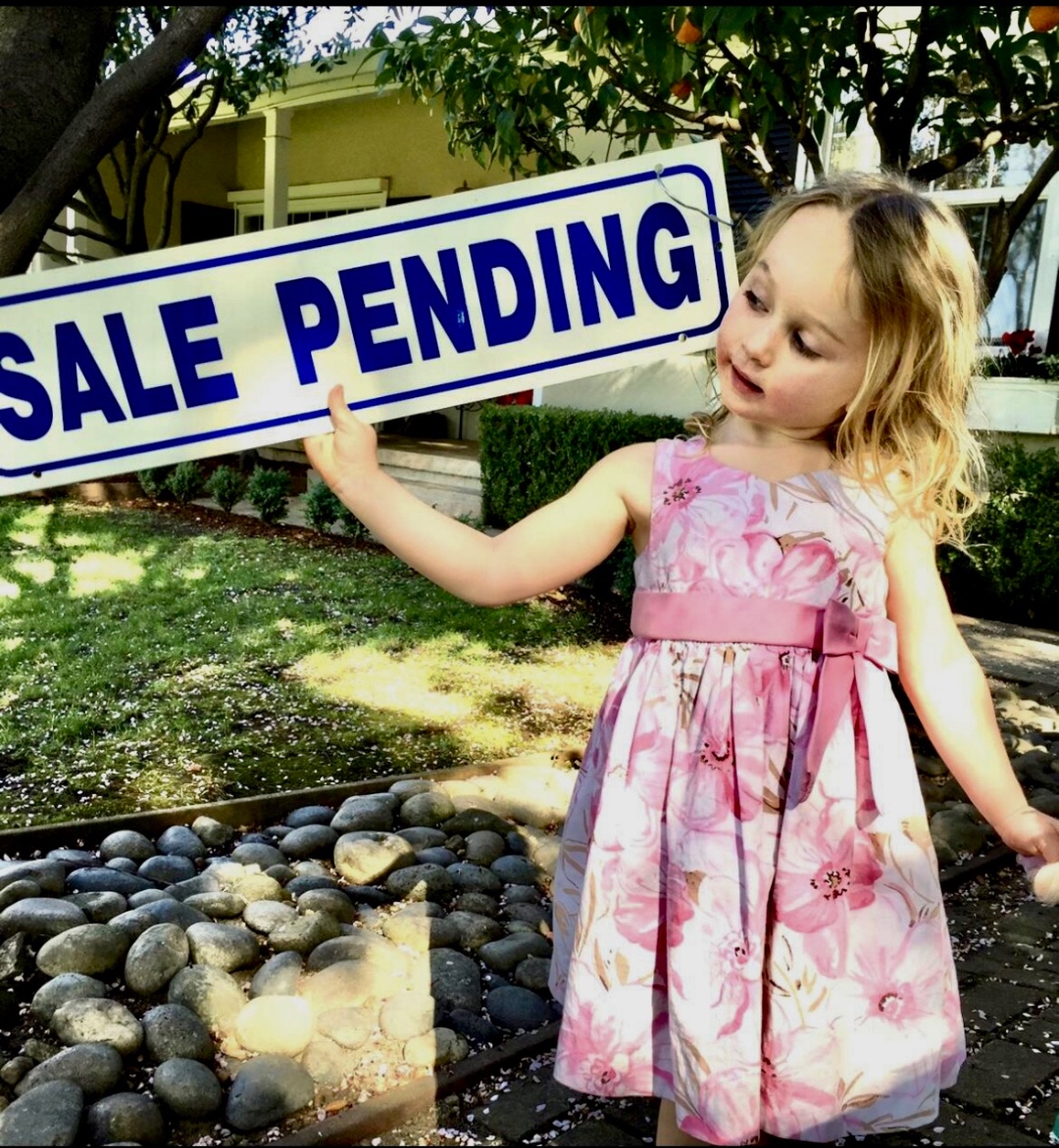 Little girl holding a Sale Pending sign in a Los Gatos garden